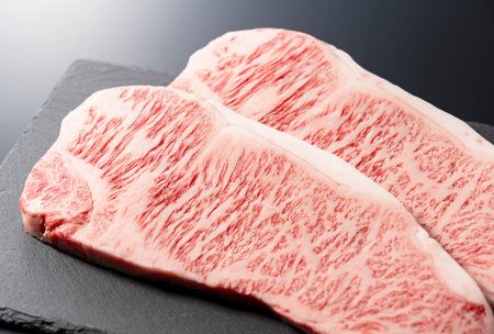 Fresh raw beef steak placed on a stone plate against a black background. Wagyu beef steak.の写真素材