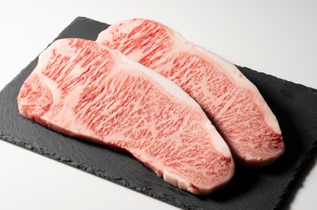 Fresh raw beef steak placed on a stone plate against a white background. Wagyu beef steak.の写真素材