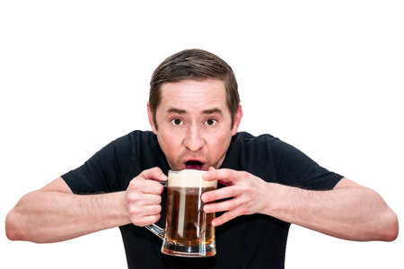 A man in a black T-shirt drinks beer while holding a glass with both hands. Isolated white backgroundの写真素材