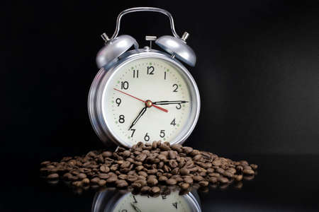 Scattered coffee beans, classic alarm clock. Morning coffee day start. Concept for advertising. Time to drink coffeeの写真素材