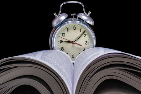 Classic alarm clock in the background of an open book. Education and study concept. Close-upの写真素材