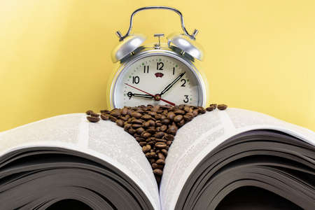 Classic alarm clock in the background of an open book. Scattered coffee. Education and study...