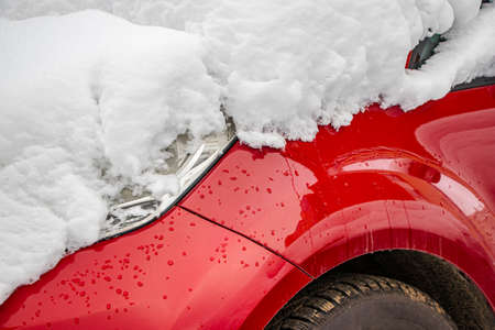 Snow-covered frozen car covered with snow. Winter road. Danger of winter driving. Car snow removal. Dangerous traffic situation.の写真素材