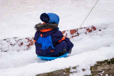 Children ride on a snow slide. Games for children in snowy weather.の写真素材