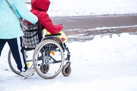 Disabled handicapped man has a hope. He sits in a wheelchair. The complexity of the movement of the disabled. On a wheelchair in the winter. Social assistance and support for people with disabilities.の写真素材