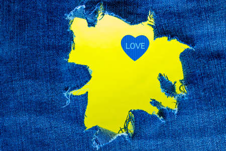 Blue heart with the inscription love on the background of torn jeans. Background for Valentine's Dayの写真素材