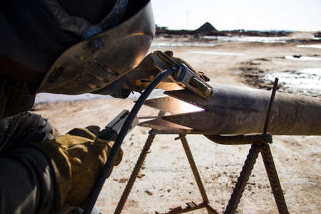 Welder in protective clothing for welding. Pipe preparation for a drilling rig. At the construction...
