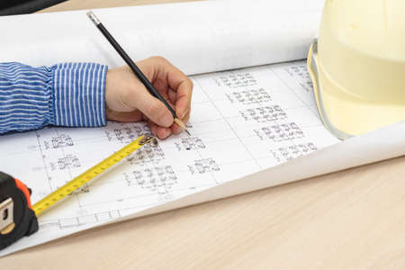 An architect is working with a project. Making changes to construction drawings. Development of a...