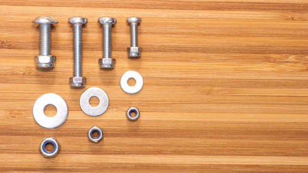 Bolts, nuts and washers of different sizes and wooden bamboo table surface. Copy space for text....