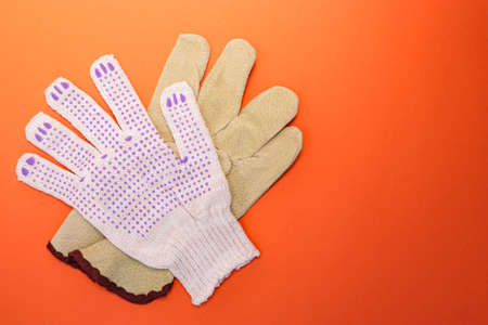 Different types of construction gloves on a bright orange background. Means of protection and...
