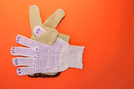Different types of construction gloves on a bright orange background. Means of protection and...