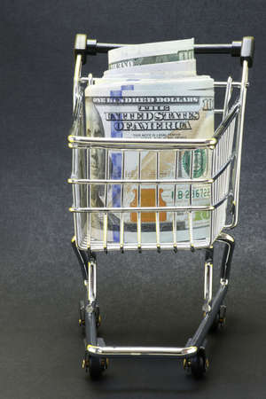 A roll of dollars in a cart from a store from. Black background. Concept for business and commerce.の写真素材