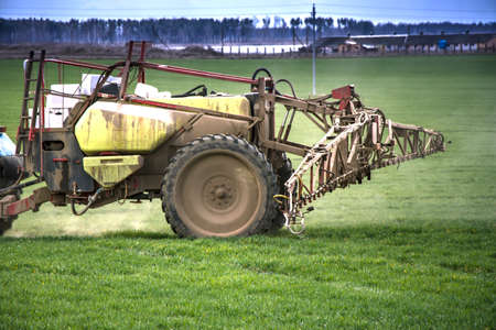 A tractor sprays a field with growth supplements and will destroy plant diseases. Agriculture....