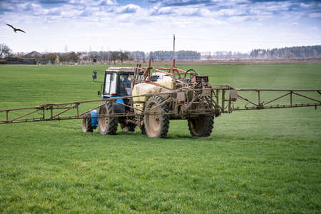 A tractor sprays a field with growth supplements and will destroy plant diseases. Agriculture....