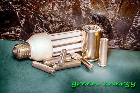 Several batteries of type AA, AAA, D and an energy-saving lamp. Green energy. Design concept.