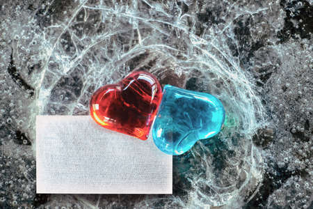 Two glass hearts red and blue on broken ice. Tablet for text. Mockup. Valentine's Day.