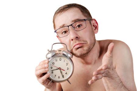 The man slept for work. A man in a raised hand holds an alarm clock. Funny facial expression. Isolated white backgroundの写真素材