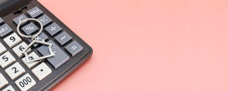 The concept of mortgage, sale and rental of housing and real estate. Mortgage credit lending. Calculator with keys and a keychain in the form of a house on a gentle pastel background. Banner format. Copy spaceの写真素材
