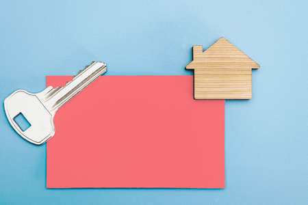 The concept of mortgage, sale and rental of housing and real estate. Business card with a key to the apartment and a mock-up of a wooden house. Copy space. Mock-upの写真素材