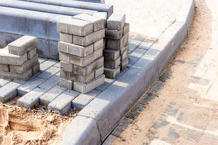 Pavement repair and laying of paving slabs on the walkway, stacked tile cubes on the background....