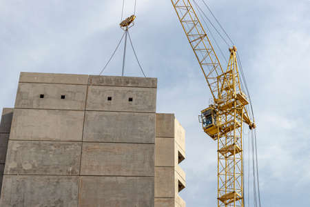 A tower crane assembles gutter panels during the construction of a panel house. Modern housing...