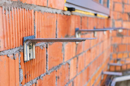 Fastening for insulation on a brick wall of a house under construction. Installation of fittings for fastening. Selective focusの写真素材