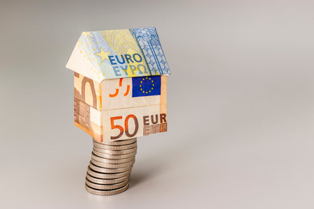 Purchase and sale of housing. Mortgage for the purchase of a house. Rental Property. A house made of euros stands on a stack of coins. Origami. Close-up. Copy space. Housing in Europeの写真素材