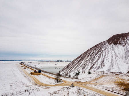 A waste heap or waste heap is a dump, an artificial embankment made of waste rock extracted during underground mining of mineral deposits. Winter landscape. Belarus. Soligorsk. Potassium saltの写真素材
