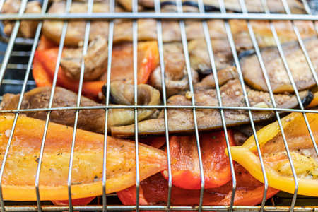 Vegetables on the grill close-up. Eggplants, peppers, mushrooms and garlic are roasted over charcoal. Vegetable grillの写真素材