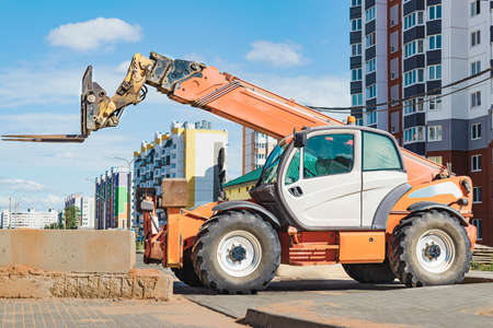 Powerful wheel forklift with telescopic mast at the construction site of a modern residential area....