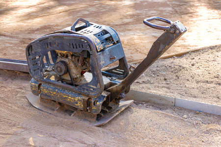 Vibratory rammer with vibrating plate on a construction site. Compaction of the soil before laying...