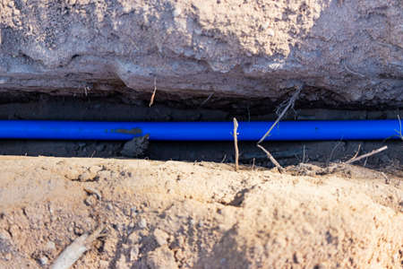 Laying a blue electrical cable in a trench in the ground. Underground communications. Electrical...