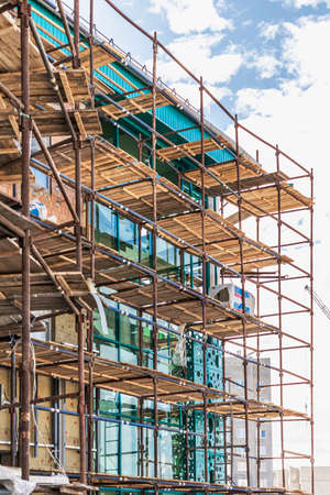 Scaffolding and scaffolding with wooden decks, against a blue sky. Performing construction work at...