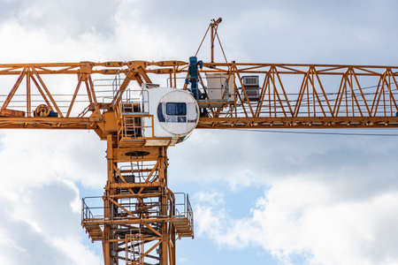 Tower crane close-up against the background of the cloudy sky. Shooting from a drone. Modern building technologiesの写真素材