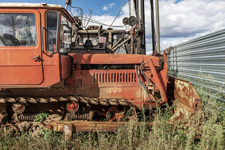 An old bulldozer machine with a heavy bucket. Earth-moving harvester with caterpillars at a construction site. Close-up. Construction heavy machineryの写真素材