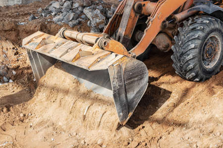 Backhoe loader moves clay soil in the excavation to the dump. Construction site planning and cutting...