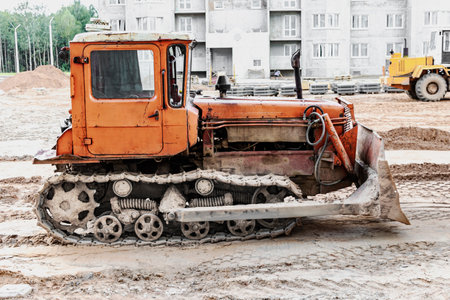 Bulldozer machine is leveling construction site. Earthmover with caterpillar is moving earth. Close-up. Construction heavy machineryの写真素材
