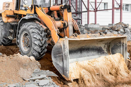 A powerful front loader on the construction site performs sanding. Moving soil with construction...