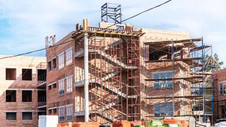 Thermal insulation of a red brick house with mineral wool. The use of scaffolding when building a...