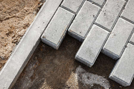Pavement repair and laying of paving slabs on the walkway, stacked tile cubes on the background....