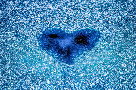 Heart on a frozen glass. Finger drawing. Hoarfrost and frost. A nice gift to your loved one. Concept for design love and romance.の写真素材