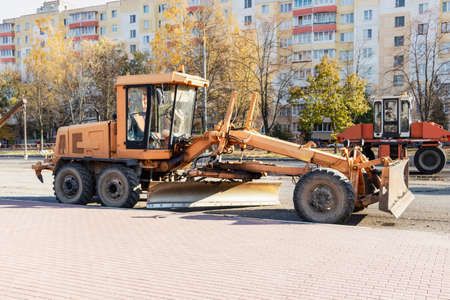 A grader performing road works in the center of a modern city. Road works in the fallの写真素材