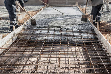 Pouring cement or concrete with a concrete mixer truck, construction site with a reinforced grillage foundation, start of construction of a production workshopの写真素材