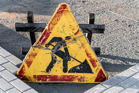 Old dented road works sign. Fencing the hazardous area where repair work is underwayの写真素材