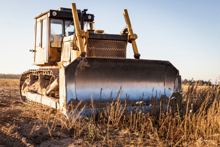 Powerful heavy crawler bulldozer works at a construction site in the evening against the background of the sky. Construction equipment for earthworksの写真素材
