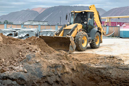 The excavator backfills the pit with the front bucket. Moves soil around the construction site....