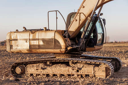 Backlit excavator on an industrial site against the background of the evening sky. Construction...