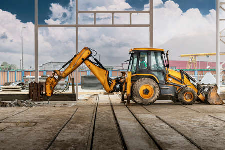 Professional demolition of reinforced concrete structures with an industrial hydraulic hammer with an excavator. Dismantling the concrete floor in the production area. Debris and crumbs of concreteの写真素材