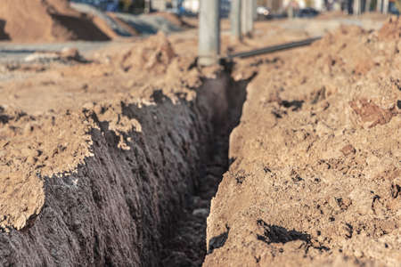 A trench in the ground prepared for laying the electrical cable at the construction siteの写真素材