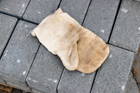 A worker's glove lying on a pallet with paving slabs. Ready-to-install concrete paving slabs. Finished products warehouseの写真素材